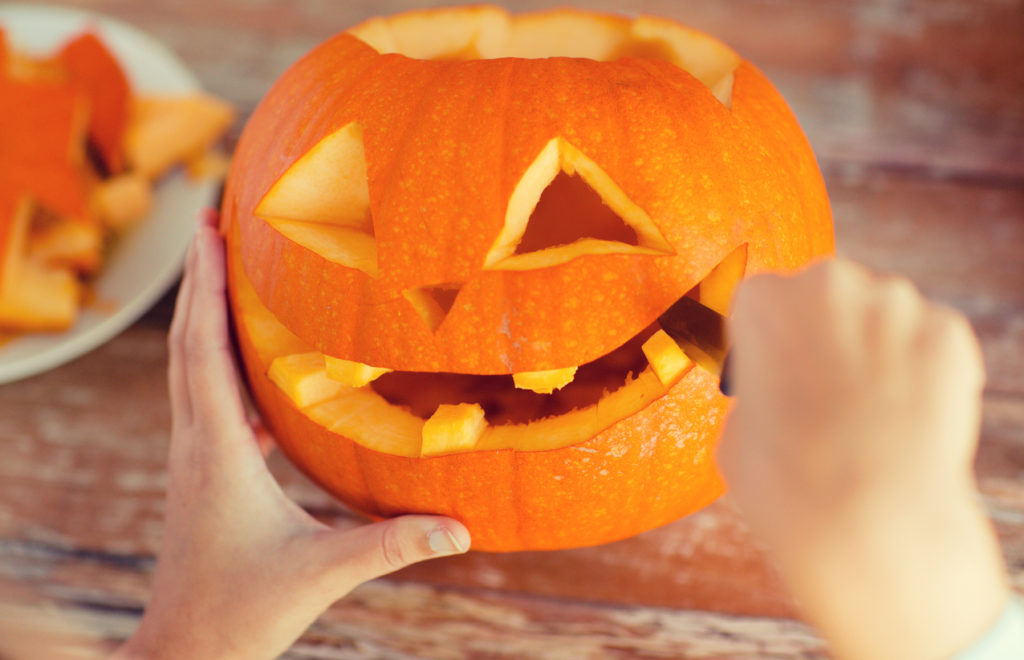 close up of woman's hands carving pumpkins at home