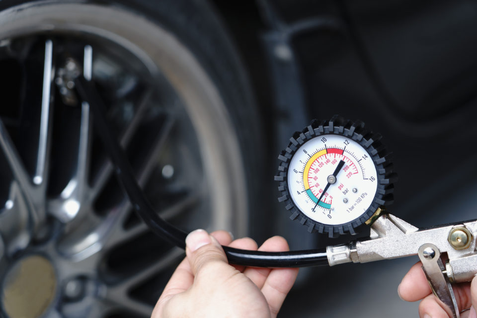 Close up mechanic inflating tire hand holding gauge pressure for checking and filling air in car tire.