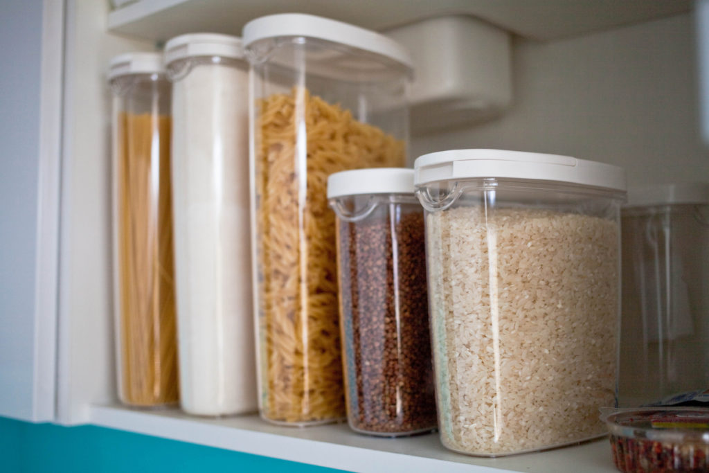 Stocked kitchen pantry with food - pasta, buckwheat, rice and sugar .