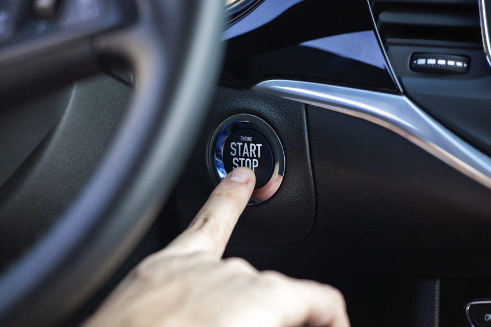 Man hand pressing car start and stop button.
