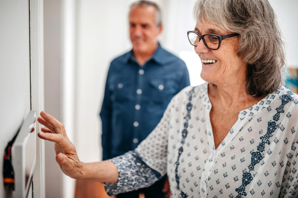 Seniors adjusting the thermostat in their home