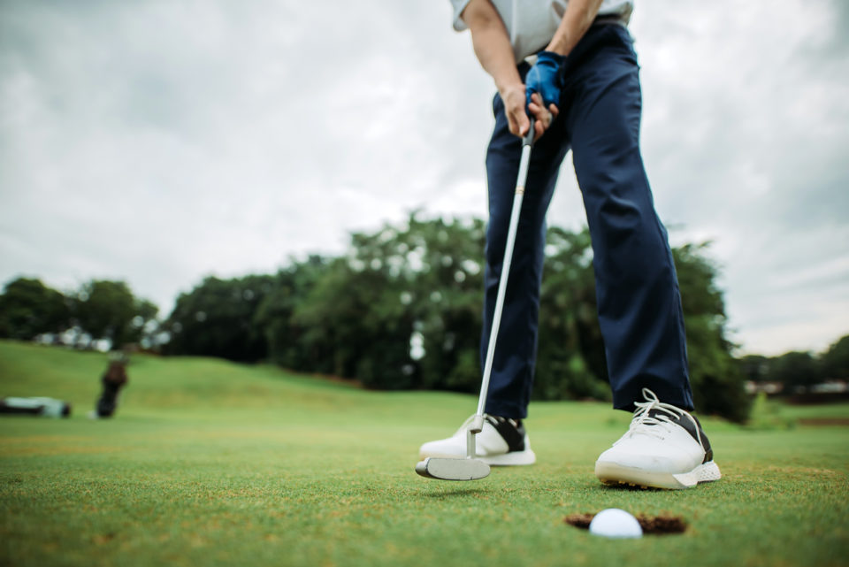 Man hitting golf ball on course