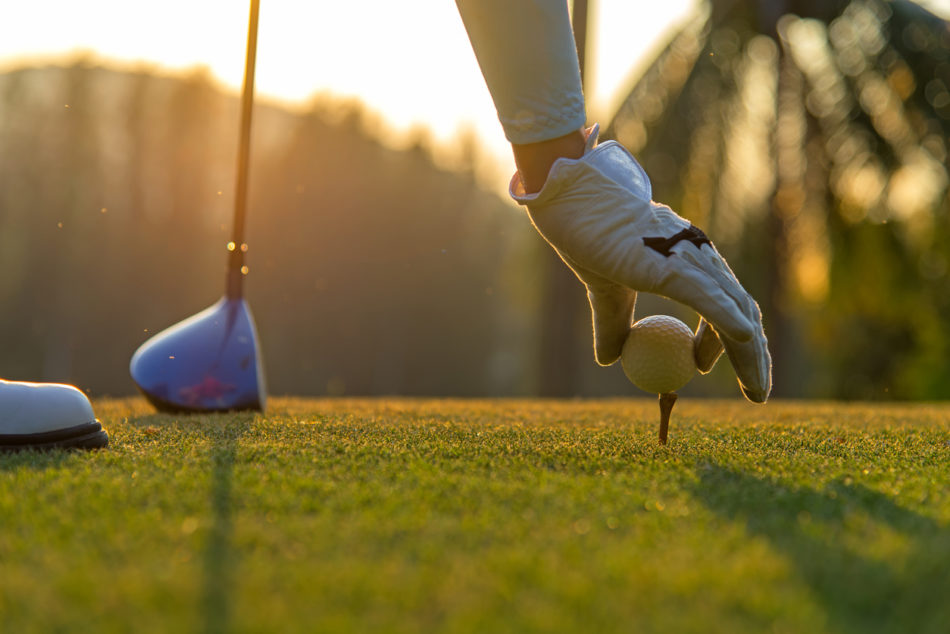 Golfer placing golf ball on the tee