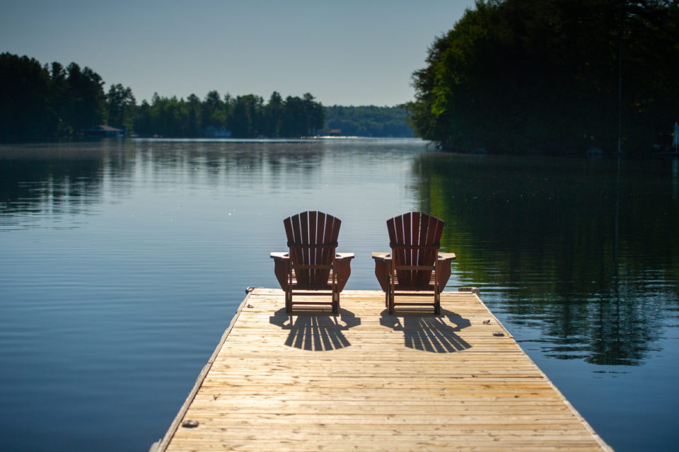 Two chairs sitting on a wooden pier facing the calm water
