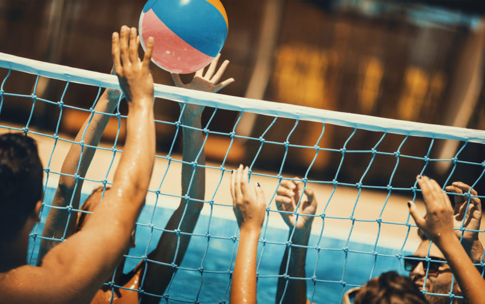 Friends playing volleyball in a pool.