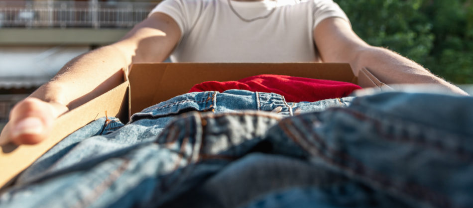 Woman holding card box with clothes inside.