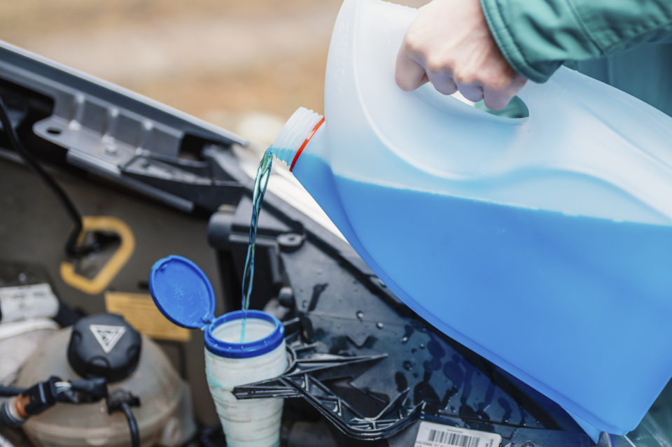 Pouring antifreeze. Filling a windshield washer tank with an antifreeze in winter cold weather.