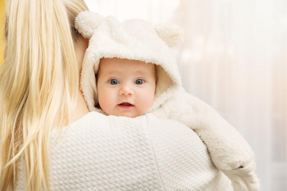 mother with her baby in fluffy bear costume over shoulder
