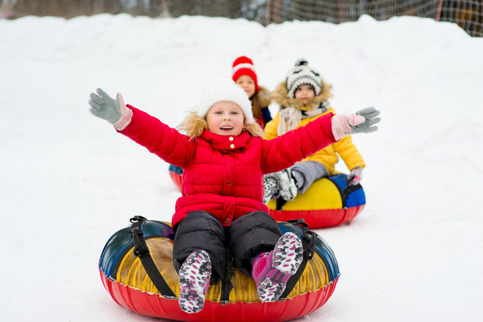 Kids on snow tubes downhill at winter day