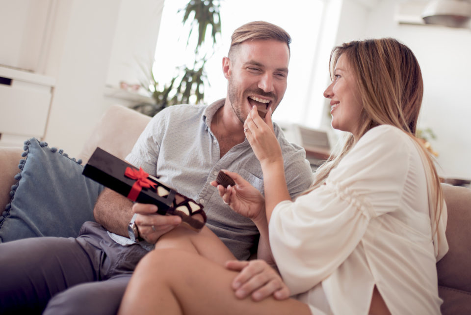 Portrait of young couple eating a heart chocolate cookie.