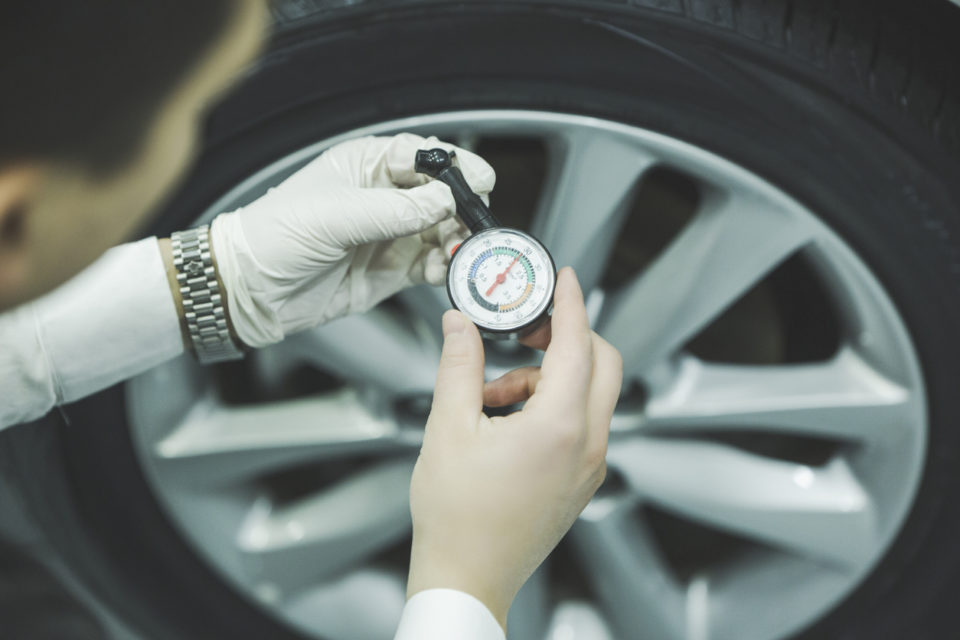 man is measuring the air pressure of the tire of a car
