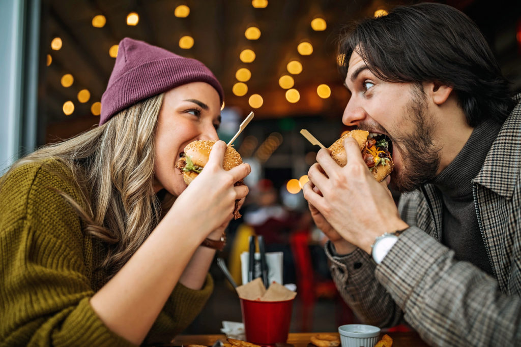 Couple enjoying cheeseburgers at restaurant together