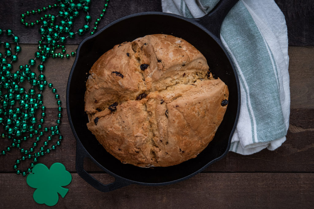 Irish Soda Bread baked in a cast iron skillet with Shamrock Beads for Saint Patrick's Day