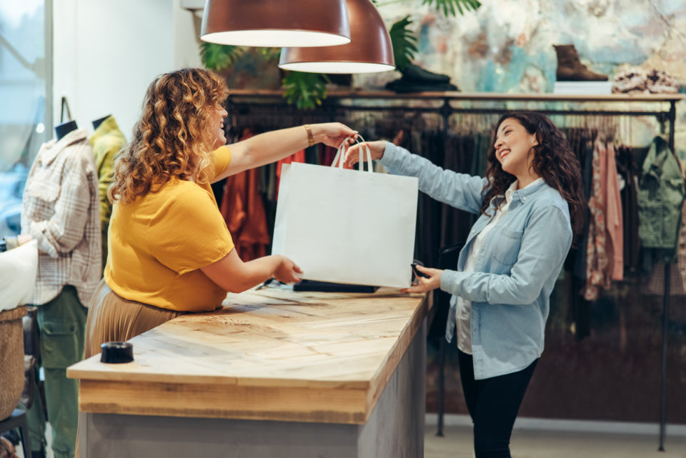 Store owner giving shopping bag to customer