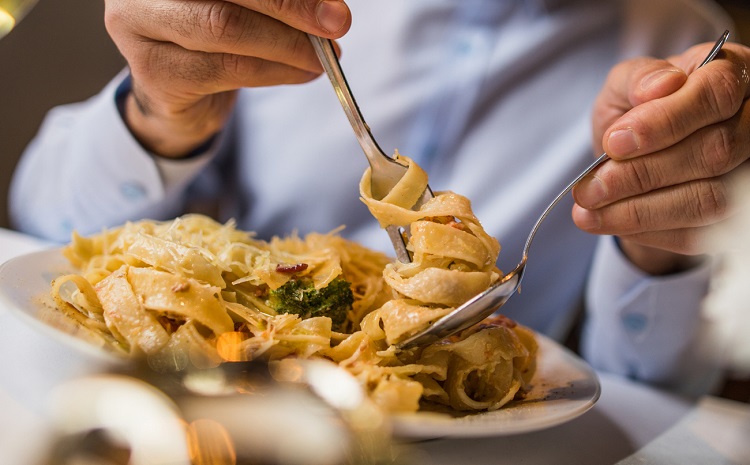 Close up of unrecognizable person eating pasta for dinner.