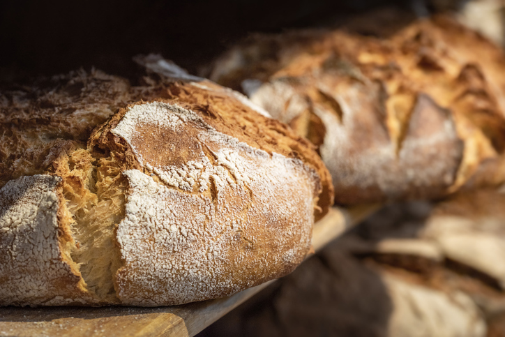 Sourdough bread close-up. Freshly baked round bread with a golden crust on bakery shelves. German baker shop context with rustic bread assortment.