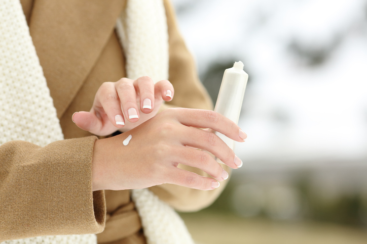 Close up of a woman hand hydrating skin applying cream in winter
