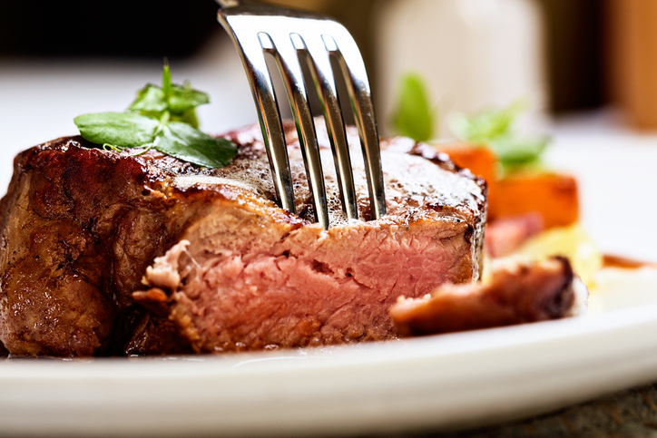 A fork pierces a juicy, succulent grilled fillet steak, grilled medium rare.
