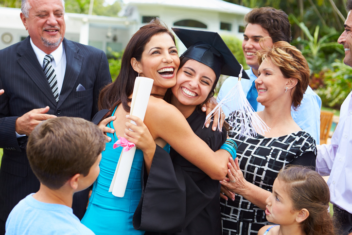 Hispanic Student And Family Celebrating Graduation Smiling And Hugging