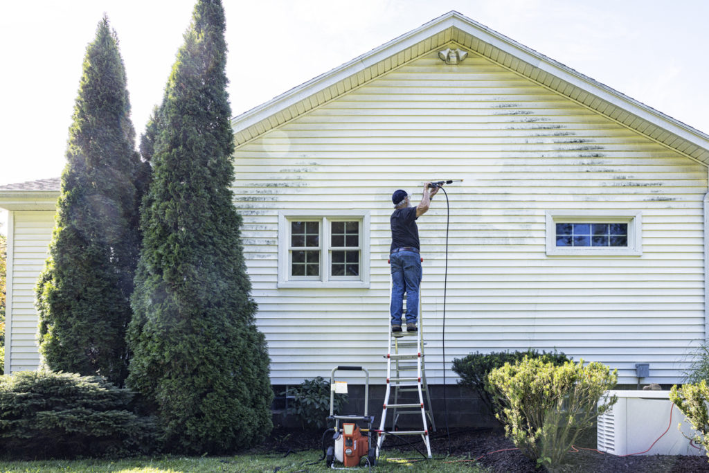 Senior Man Up On Ladder DIY Power Washing House Siding