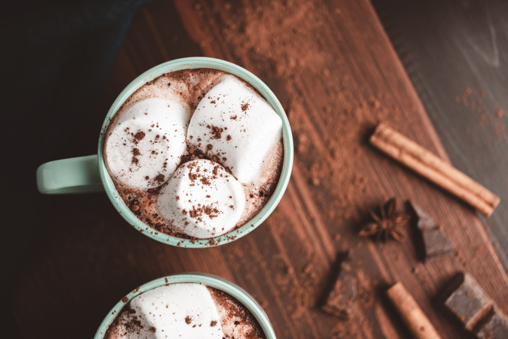 Hot chocolate drink with marshmallow in a cup on wooden board with cinnamon and star anise