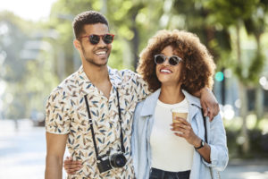 Smiling young couple walking arm in arm on sidewalk.