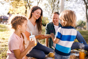 Happy family enjoying a picnic at the park while mother is giving them cookies for snack.